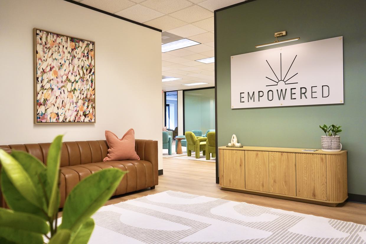 Reception at Empowered Treatment, with the Empowered wordmark on a deep green wall